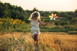 Cute little girl playing in the summer field of wheat