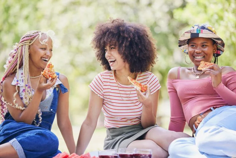 Friends picnic in park, people happy on holiday in New York summer and eating pizza outdoor