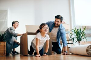 Playful family having fun with carton boxes while relocating into a new home. Focus is on daughter.