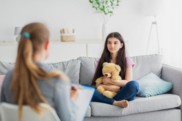Female psychologist consulting with depressed teenage girl at office, adolescent mental health