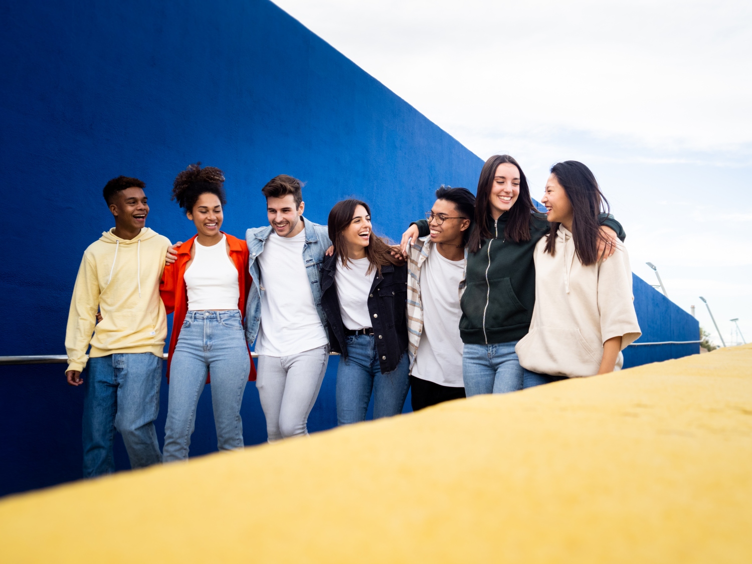 Group of multiethnic young friends walking through the city laughing holding each other