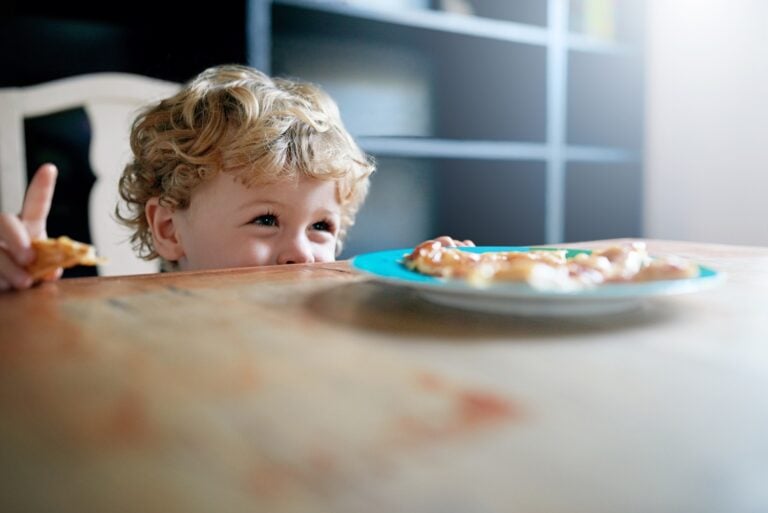 young boy happily eating in the dining table