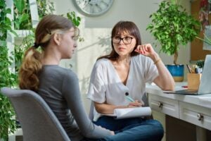 Woman psychologist, counselor talking with teenage girl