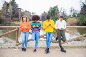 multiethnic friends outdoor standing close using smartphones and social media
