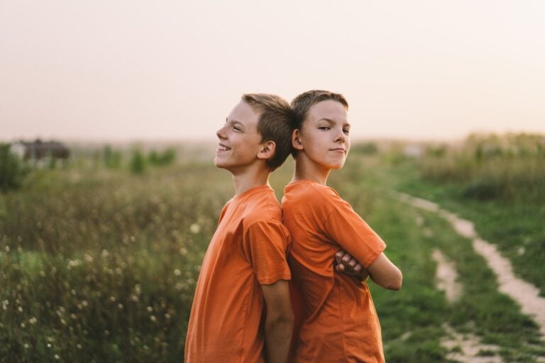 twin brother boys playing outdoors on field at sunset, concept of children's mental health