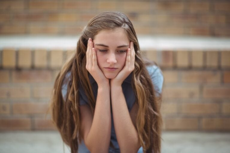 Sad schoolgirl sitting alone in campus