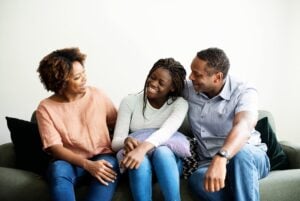 parents and teenage daughter smiling at each other during a family therapy session