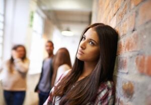 teenage lady leaning against the wall, looking ahead, concept of depression, eating disorder