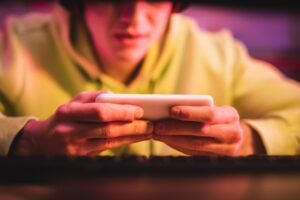 anonymous teenager using mobile phone to surf the internet and play games, gaming addiction concept