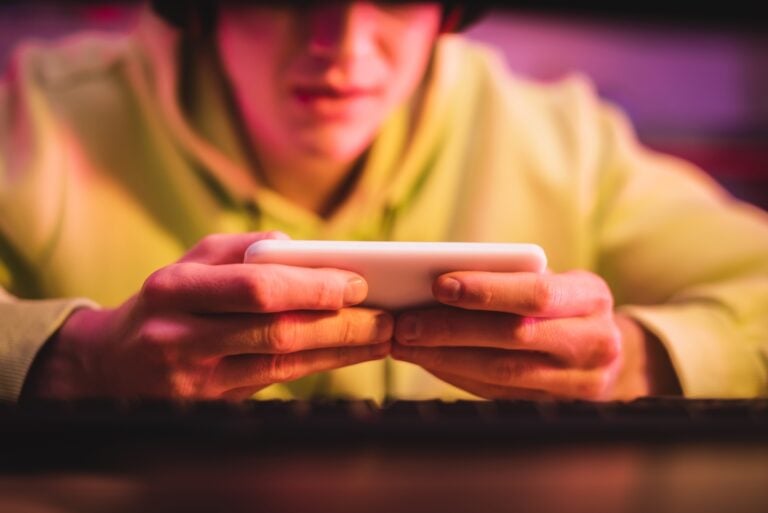 anonymous teenager using mobile phone to surf the internet and play games, gaming addiction concept