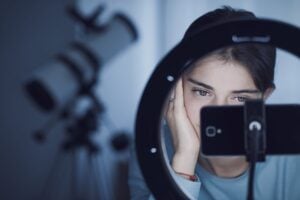 close up shot of a teenage girl looking at her mobile phone connected to a studio ring light