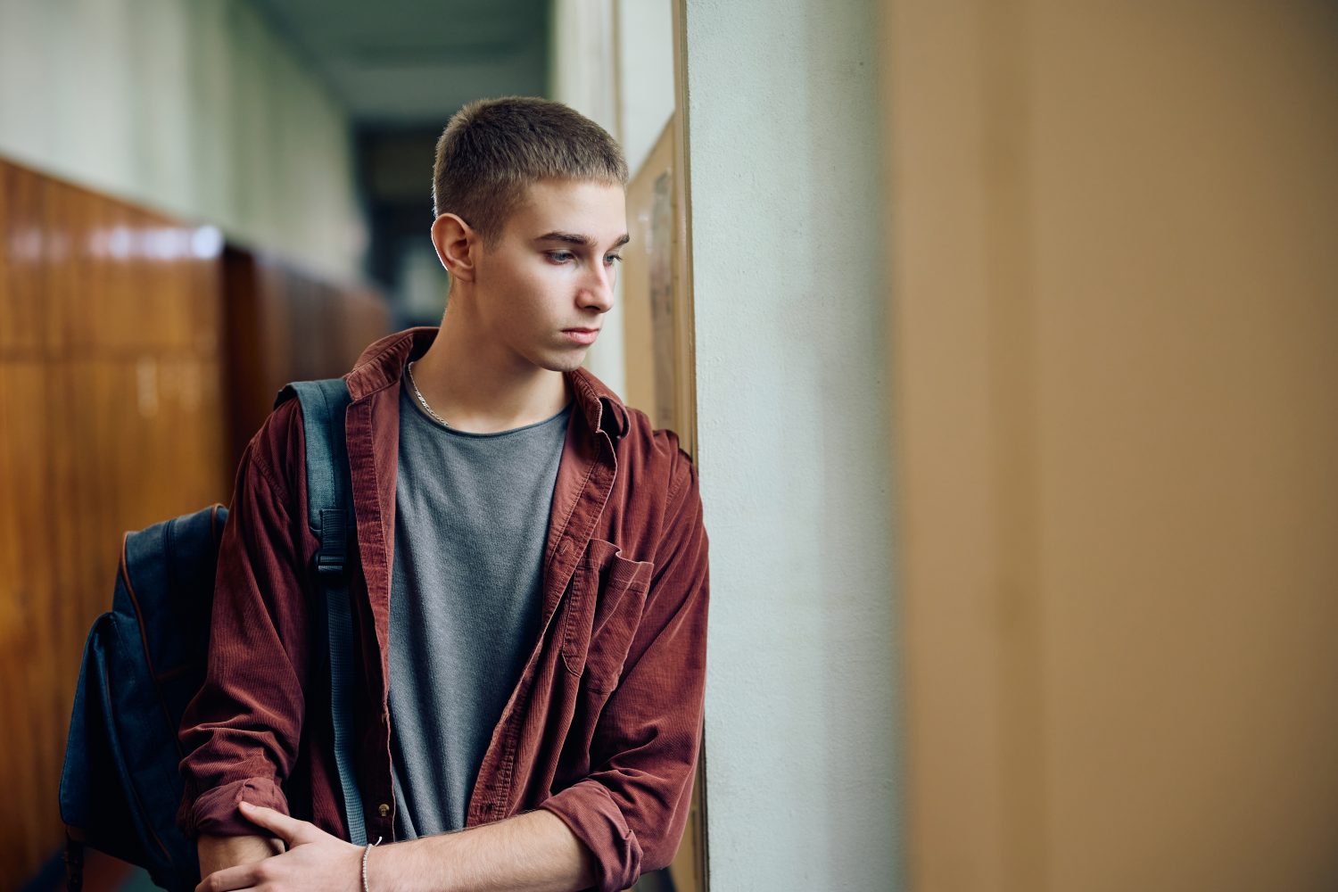 high school student looking through the window in a hallway