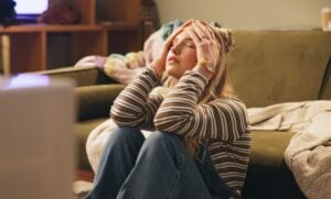 teenage girl sitting at home, looking stressed and tired