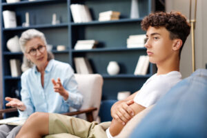 Teenager boy feeling sad during therapy session with psychologist
