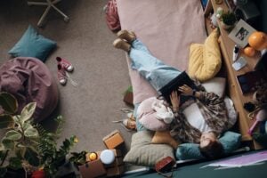 Teenage Girl Relaxing on Bed Using Laptop in Cozy Bedroom Setting
