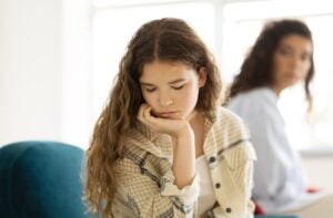 teenage girl looking sad, back turned to mother, concept of teenage mental health struggles