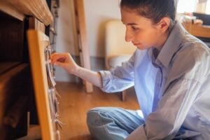 Close-up of a young woman in casual clothes sitting on the floor in front of a cork board
