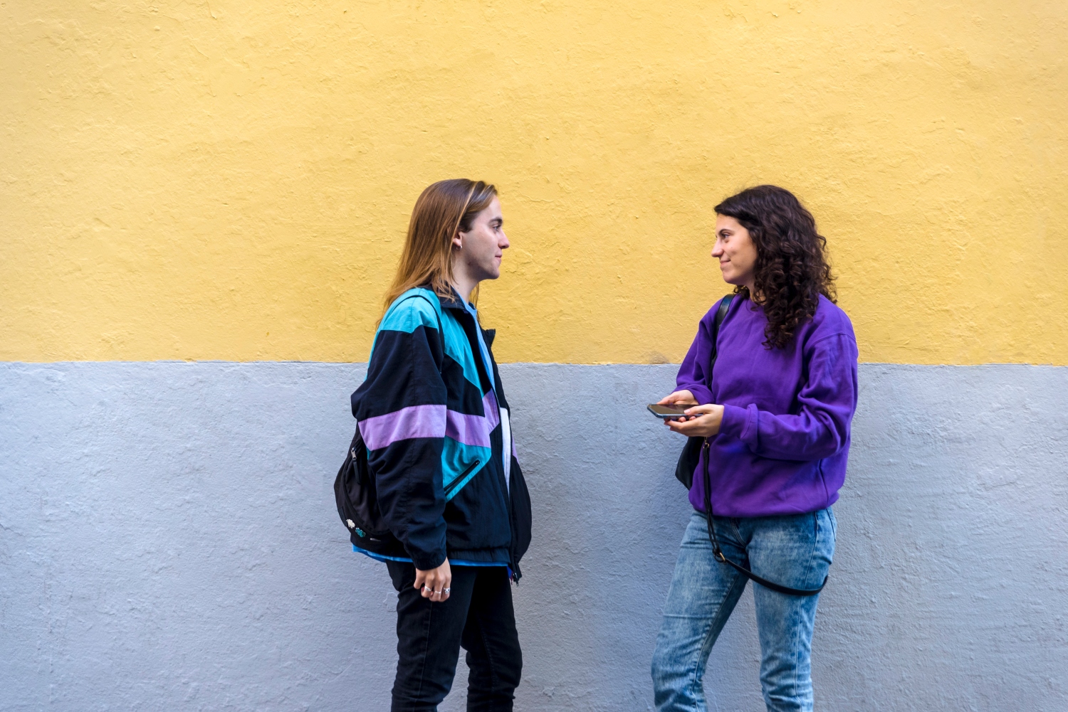 Young friends talking standing outdoors on the street. Friendship concept.