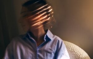 blurred image of a young woman, face obscured by shadow and light, concept of mental health