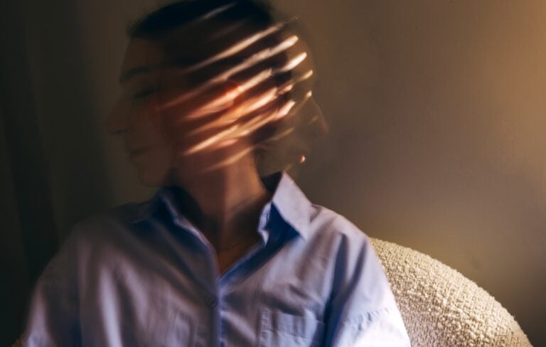 blurred image of a young woman, face obscured by shadow and light, concept of mental health